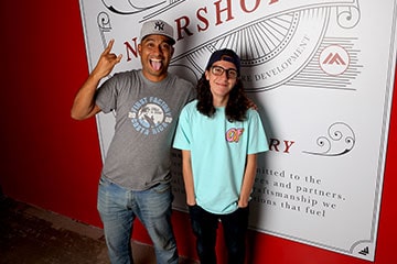 Two male employees wearing baseball hats in front of the nearshore office sign