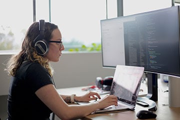Female software engineer in front of a laptop and computer monitor