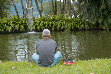 Employee enjoying Costa Rica's nature taking a break sitting in the grass by the river