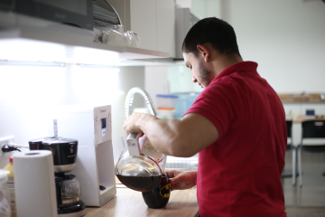 Software developer enjoying the office perks serving a cup of coffee in the kitchen