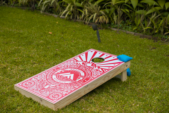 First Factory's red and white branded Cornhole game, outdoor entertainment for our employees